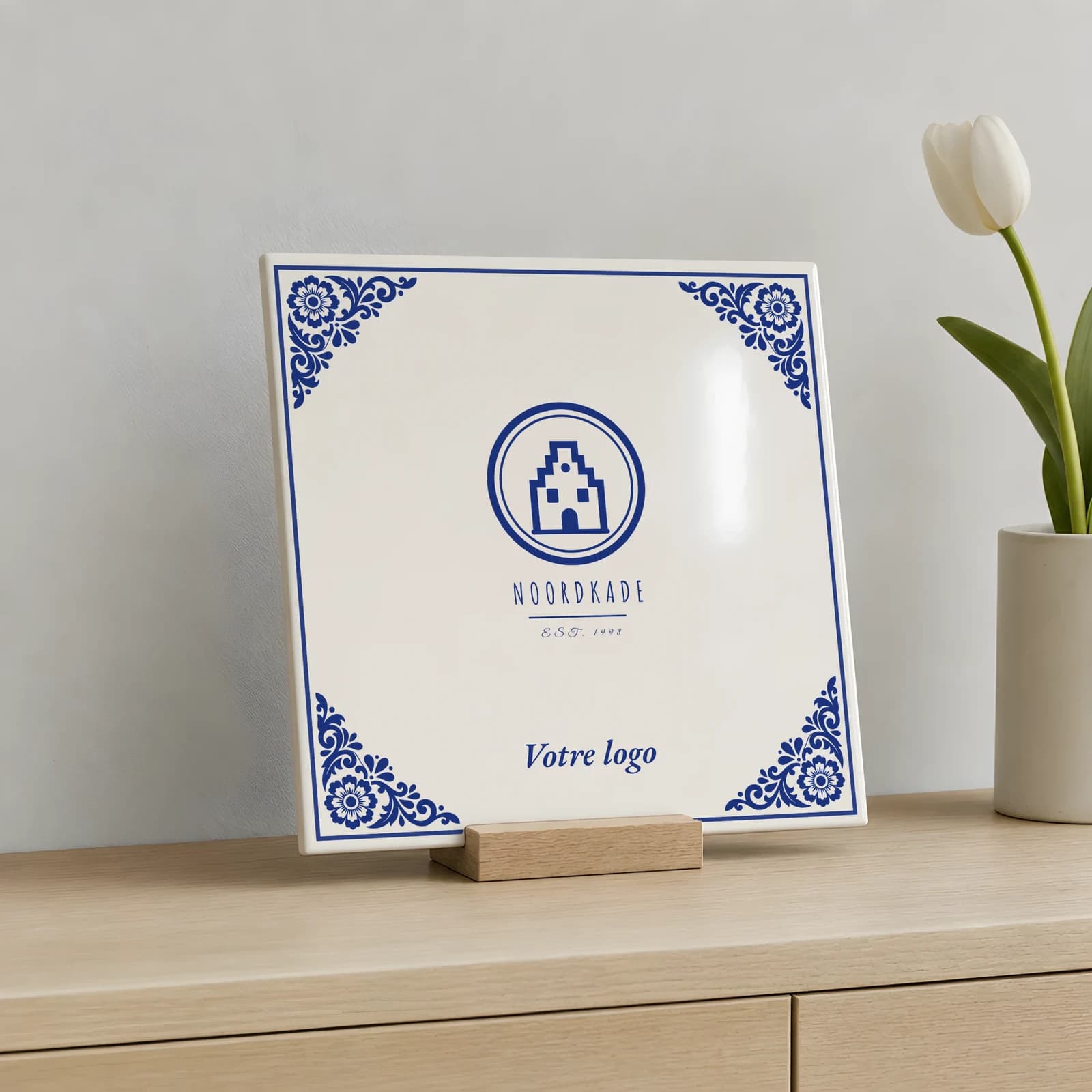 Carreau logo bleu de Delft sur un support en bois, posé sur un buffet